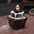 Ceramic backflow incense burner in dark brown with smoke flowing on bamboo mat - Lucky Turning