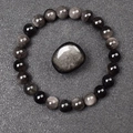 Macro view of 8mm natural obsidian beads and polished stone on a textured surface - Silver Obsidian