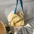Close-up of yellow and white striped canvas tote bag with blue pleated handle on a sofa - Yellow Stripes