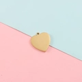 Primer plano de un colgante de corazón de oro pulido sobre fondo rosa y azul para joyería DIY - Chapado en Oro 18K