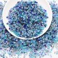 Detailed top view of mixed blue square glass beads in a white bowl for DIY jewelry - Blue Series