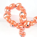 Macro shot of orange heart-shaped ceramic evil eye beads with glossy finish for jewelry DIY - 13x14mm / Orange Red