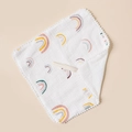 Close-up of cotton baby bib featuring rainbow patterns and white pom-pom trim detail - White Rainbow And White