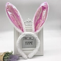 Detailed view of white plush bunny ears headband with pink sequins against a photo frame - Pink AB Rabbit