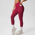 Detail of high waisted burgundy yoga leggings featuring side pockets for phone storage - S / Bottoms / Carmine