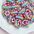 Macro detail of hand-painted colorful resin beads with floral patterns in a white tray - Trans Red Bead + Red Green White Cream + Red Heart