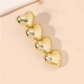 Detail von vier goldenen Legierungsherzen auf einer glatten Haarklammer mit Glanz - Gold