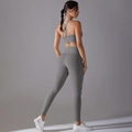 Detail of the cross-back sports bra and high-waisted gray yoga leggings on a model - Titanium Gray