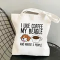 White canvas tote bag featuring a Beagle cartoon and coffee slogan on a metal chair - C21 Coffee Beagle and 3 People