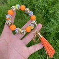 Detail of colorful beaded keychain bracelet with orange leather tassel and gold ring - Orange Stripe Leopard Style / Orange