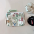 Detail of floral cotton zip pouch with green leaf print next to makeup accessories - Yellow Berry Print
