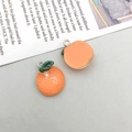 Dettaglio ravvicinato di ciondoli in resina a forma di arancia con foglie per gioielli - 1 Pezzo Mandarino in Resina Arancione