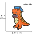 Cute orange dinosaur enamel pin with graduation cap and book, 1.14-inch badge accessory - Orange Graduation Dinosaur