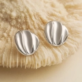 Macro shot of silver plated heart-shaped geometric stud earrings on a coral texture - Silver Irregular Round