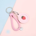 Pink faux leather AirTag case with 3D strawberry charm and woven lanyard strap - Hand Strap Style - Pink Strawberry