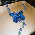 Dettaglio macro del ciondolo a farfalla blu intrecciata e perle di vetro sulla collana - Collana di perle di vetro a farfalla ricamata blu