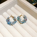 Dettaglio di orecchini a cerchio in filo d'oro con pietre naturali blu e perline - Perno in argento - Oro - Blu