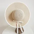 Cappello di paglia con bordo in pizzo bianco e nastro a fiocco su sfondo bianco - Taglia unica / Beige