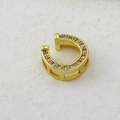 Close-up of golden C-shaped ear cuff with pave cubic zirconia on textured background - Gold Ear Bone Clip