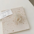 Gros plan d'une pince à cheveux minimaliste blanc crème sur une plaque de pierre - Blanc