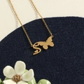 Golden butterfly necklace with letter S pendant on a blue velvet display stand - Gold S