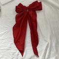 Elegant large burgundy bow hair clip with long ribbons on a white textured background - Red