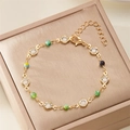 Pulsera de cuentas doradas con motivos florales coloridos y dije de corazón en un joyero - 008 Cuenta / Pulsera