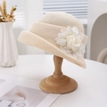 Elegant French knit straw hat with large floral accent and rhinestones on a stand - Off White