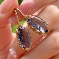 Macro shot of oval purple gemstone earrings with gold prong settings and fish hooks - Dark Blue