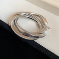 Nahaufnahme des dreilagigen silbernen Spiralschlangenarmbands auf Texturhintergrund - Dreilagige Spiralstruktur / Silber