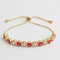 Macro detail of adjustable gold evil eye bracelet with red enamel and clear zircon stones - Red
