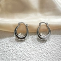 Detail view of silver crescent hoop earrings resting on white texture and gold silk fabric - 20mm / Silver