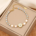 Evil eye beaded bracelet with gold accents and pearls on a premium jewelry box display - Light Blue