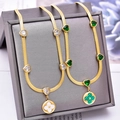 Goldene Schlangenkette mit Herz-Zirkonia und Kleeblatt-Anhänger in eleganter Präsentation - Gold Grün Zirkon Kleeblatt Kreis