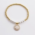 Detail of beaded bracelet featuring gold copper beads, white pearls and a zircon smiley face charm - White
