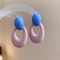 Vista macro de pendientes ovalados de acrílico bicolor en azul y rosa sobre soporte - Poste de pendiente de plata - Rosa