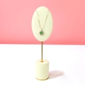 Gold necklace with green opal pendant and white diamonds on white jewelry display stand - Beige