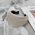 Close-up of beige striped fabric headband with anti-slip teeth on soft white fabric background - Beige