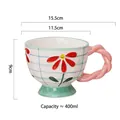Hand-painted ceramic breakfast mug with red floral patterns and pink twisted handle - Daisy