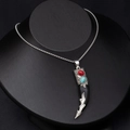 Detail of vintage faux wolf tooth pendant with red and turquoise stones on a silver chain - Black Wolf Tooth with Turquoise