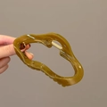 Olivgrüne gewellte Haarklammer aus Harz mit lichtdurchlässigem Finish in der Hand - Olivgrün