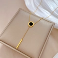 Detail of a gold titanium steel Y-necklace with black round pendant and long gold bar - Titanium Steel / Gold
