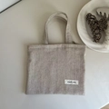 Detail of oat-colored linen mini tote bag featuring the simple wish stitched fabric label - Solid Beige