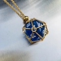 Necklace with blue D20 dice pendant in gold metal mesh cage on metallic background - Gold Cage with Royal Blue Dice