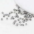 Close-up of silver-plated cylindrical spacer beads on white fabric for DIY jewelry - 2x2mm / Platinum Color