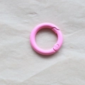 Single pink coated metal spring ring O-ring fastener on a textured beige background - Deep Pink