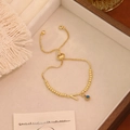 Dettaglio del bracciale a sfere dorate con lettera V in cristallo e ciondolo occhio blu - Lettera V