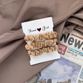 Set of 3 champagne gold satin scrunchies displayed on aesthetic newsprint background - Champagne Gold