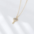 Detailed view of a gold key pendant with micro-pave zircons on white silk background - 925 Silver / Gold