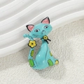 Cartoon teal cat enamel brooch featuring yellow flowers and green spots on a white stand - Light Blue Cat